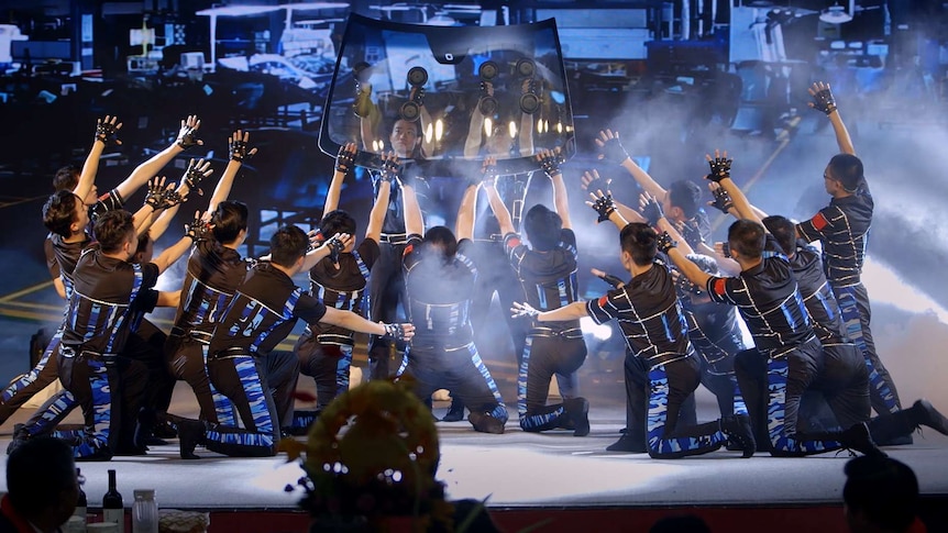 A group of people perform a musical number paying tribute to windshields