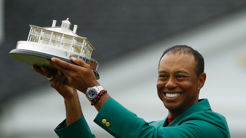 Tiger Woods wears his green jacket holding the winning trophy after the final round for the Masters golf tournament Sunday.