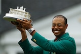 Tiger Woods wears his green jacket holding the winning trophy after the final round for the Masters golf tournament Sunday.