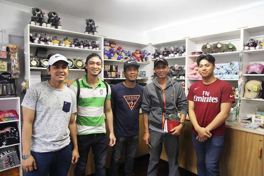 Five men stand inside an Australiana gift shop