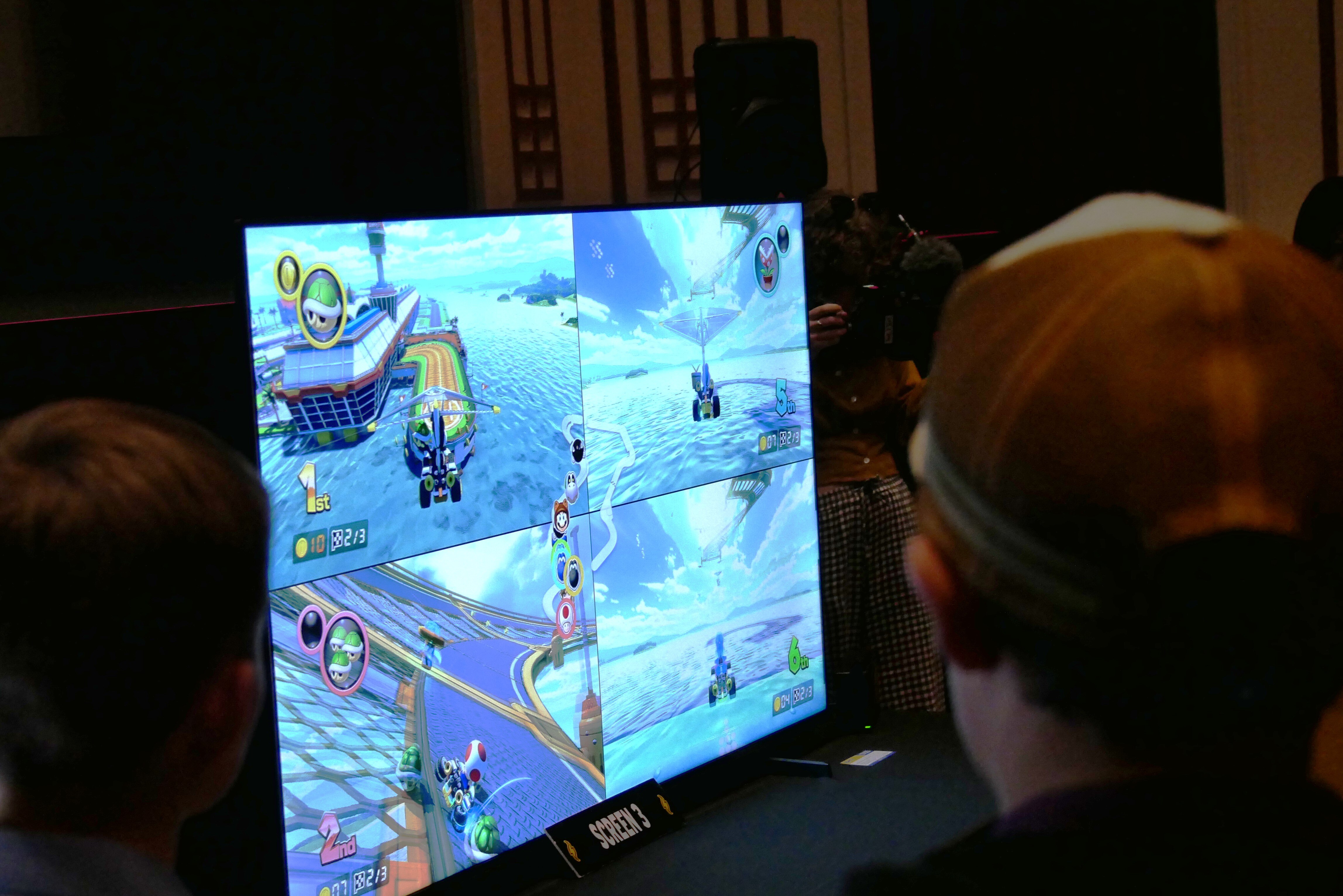 The back of a boy&#x27;s head who is wearing a cap looking on at a tv screen with a game on it.