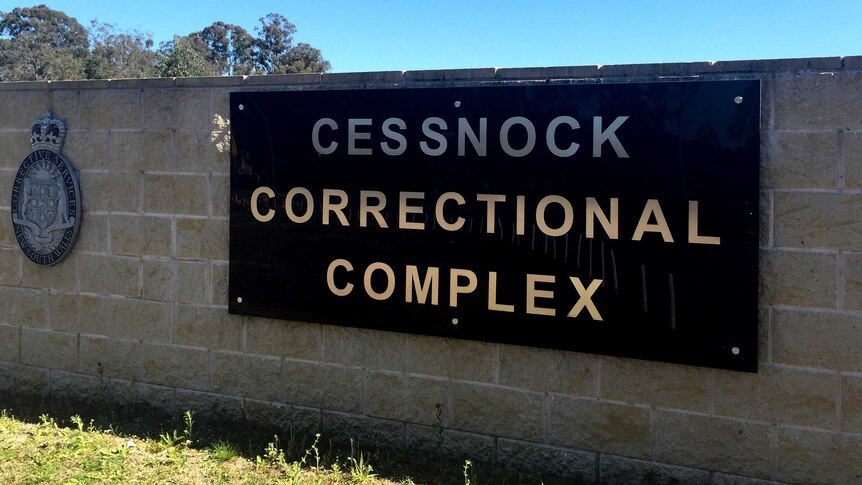 A wall made of large bricks bearing a sign that reads "Cessnock Correctional Complex".