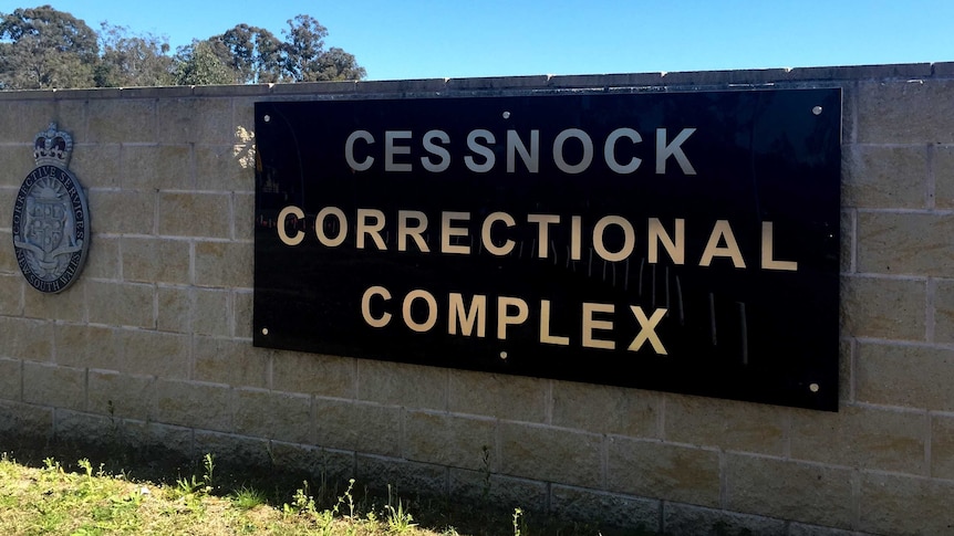 A brick wall with a sign reading 'Cessnock Correctional Complex' affixed to it.