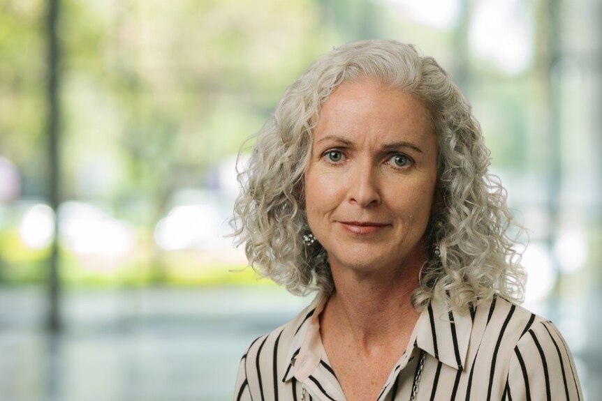 An older woman with white wavy hair looks at the camera