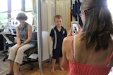 A mother takes a photo of her child in a uniform