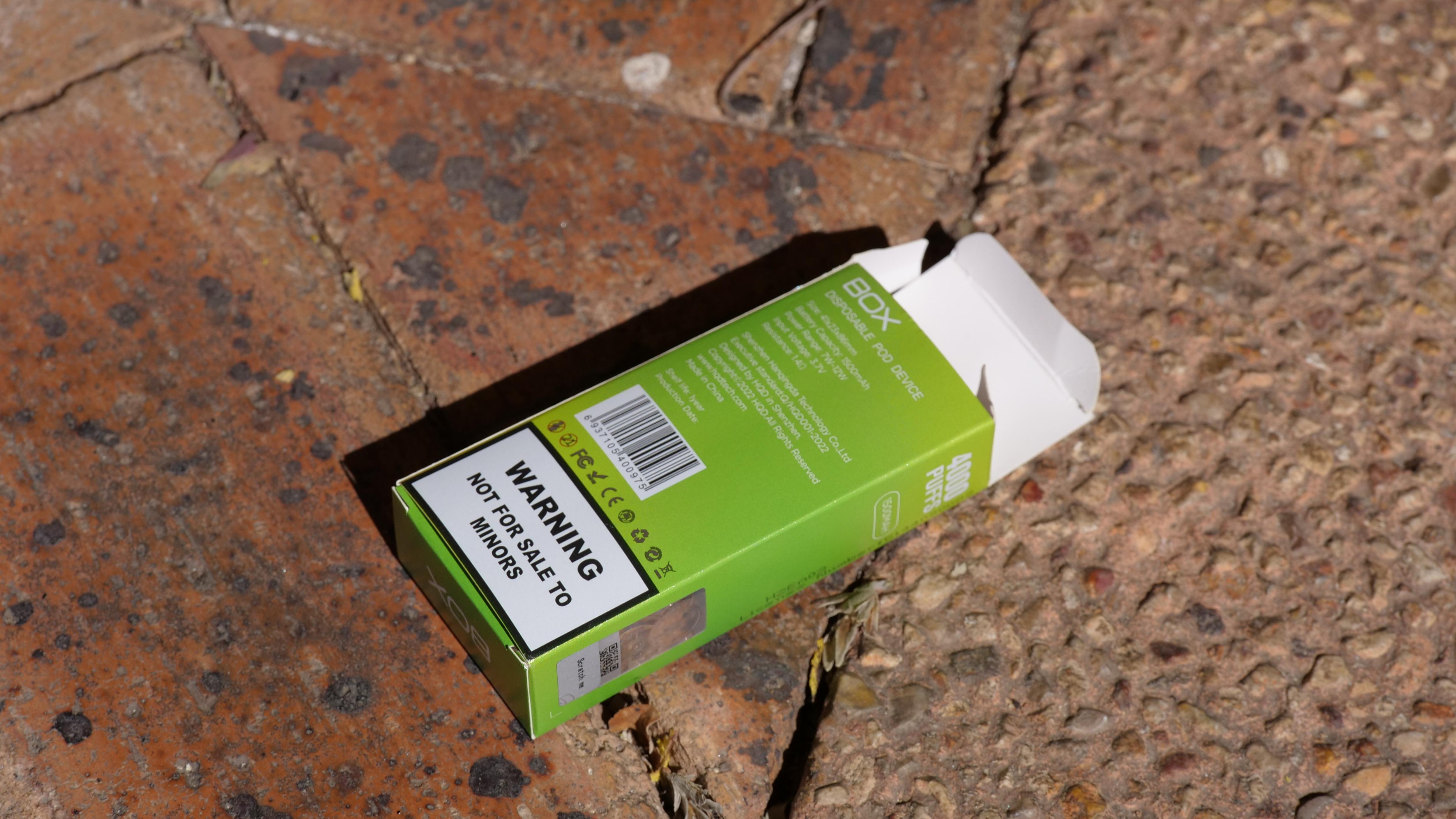 Una caja de vapeo vacía con una inscripción en la etiqueta. "Atención, no está destinado a la venta a menores." está en un sendero.