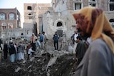 A group of people stand on a pile of rubble.