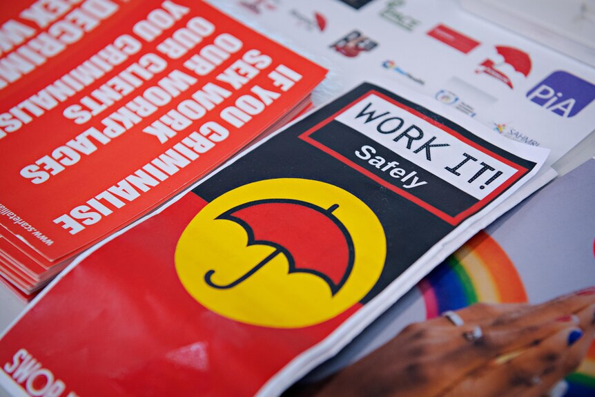 Piles of pamphlets and stickers on a table. The one on focus says 'Work It Safety'