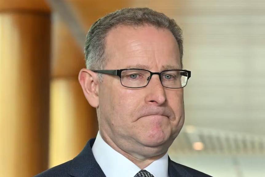 A middle aged man in a suit with a glum look on his face 