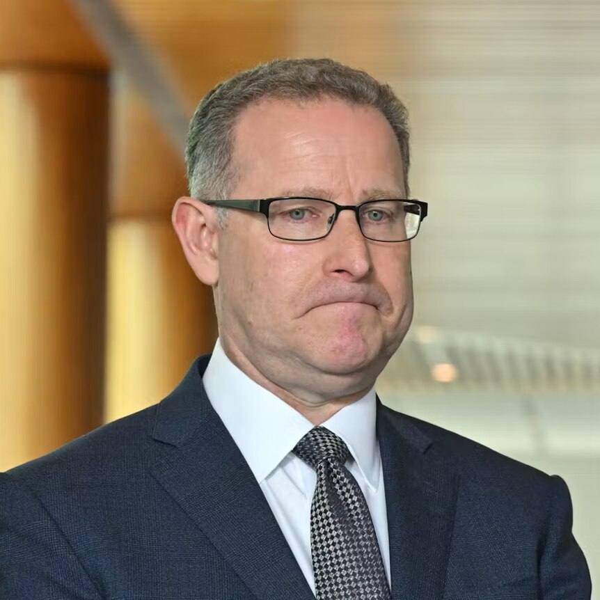 A middle aged man in a suit with a glum look on his face 