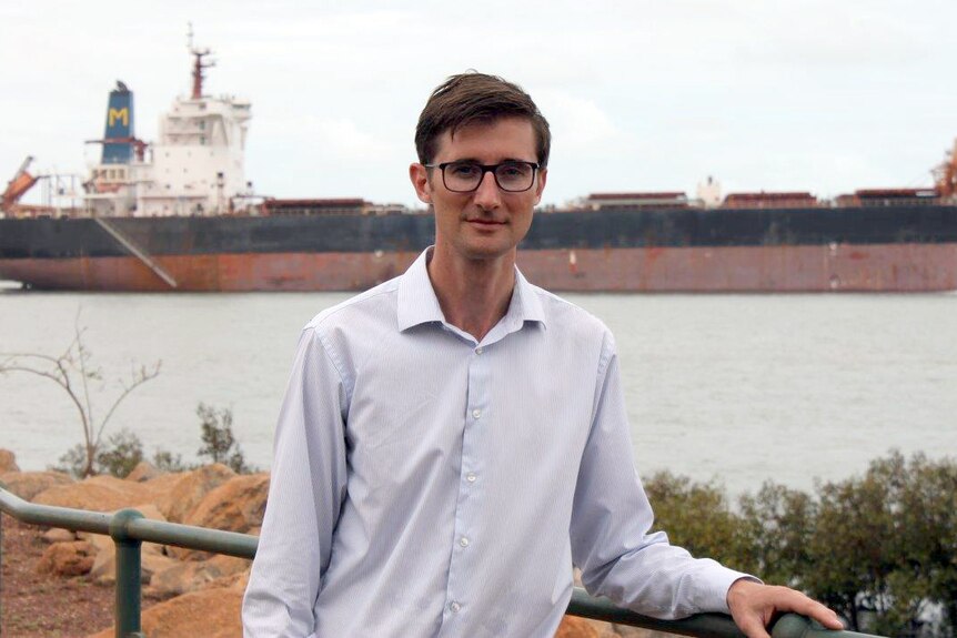 Mark Alchin standing near the port, with a cargo ship in the background.