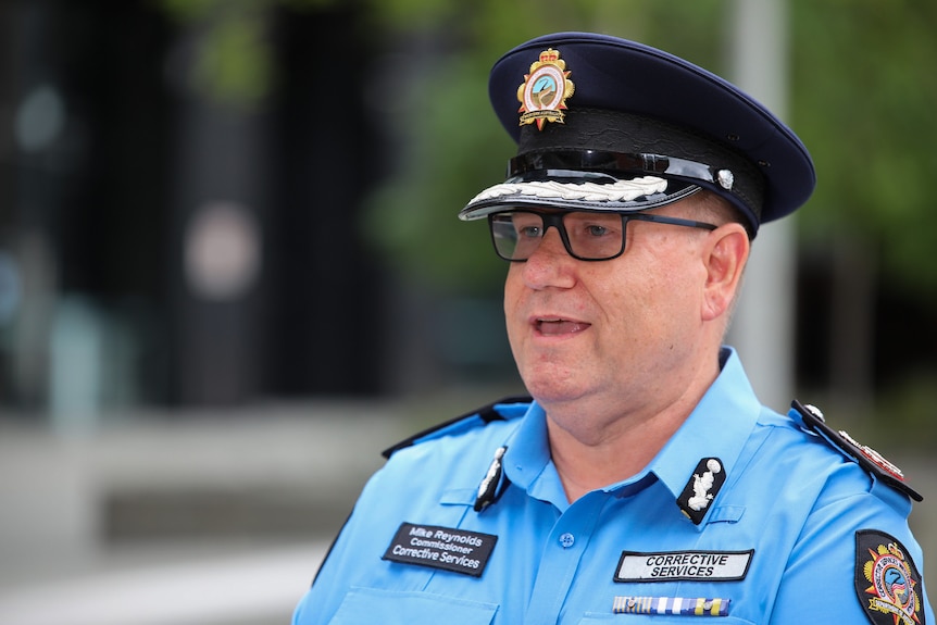 A man in a uniform similar to a police officer's talks to the media