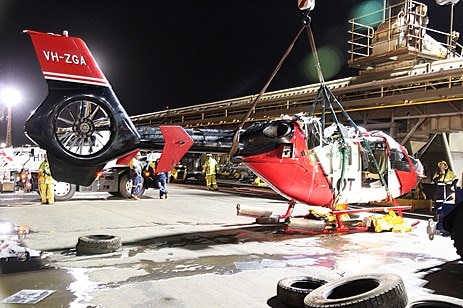 A helicopter being lifted onto the dock of a ship