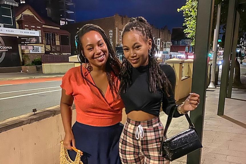 Two young women hug on the street