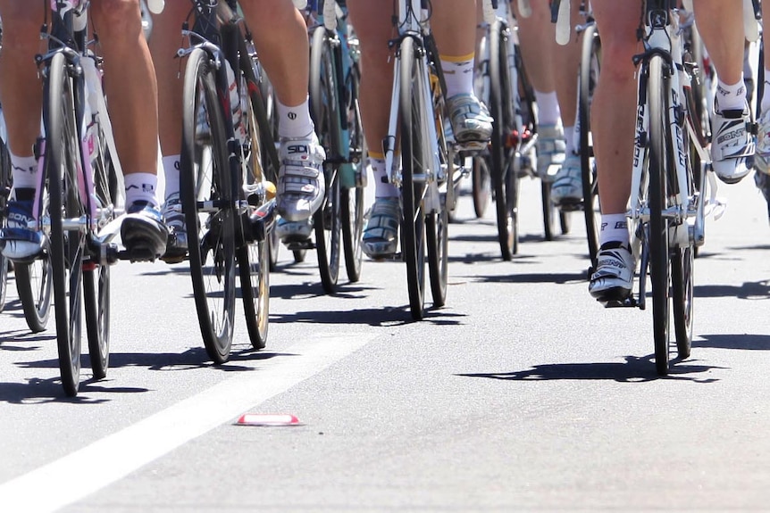 Group of cyclists ride along a road.