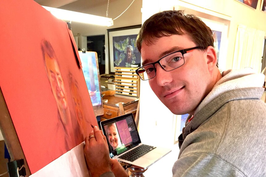 Cerebral palsy and autism sufferer Joshua Adam paints a portrait of a woman as he looks at the camera.