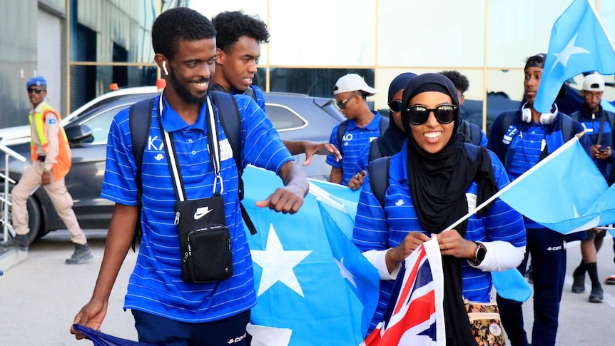 Amina Liban walking with other African-Australians holding an Australian flag.