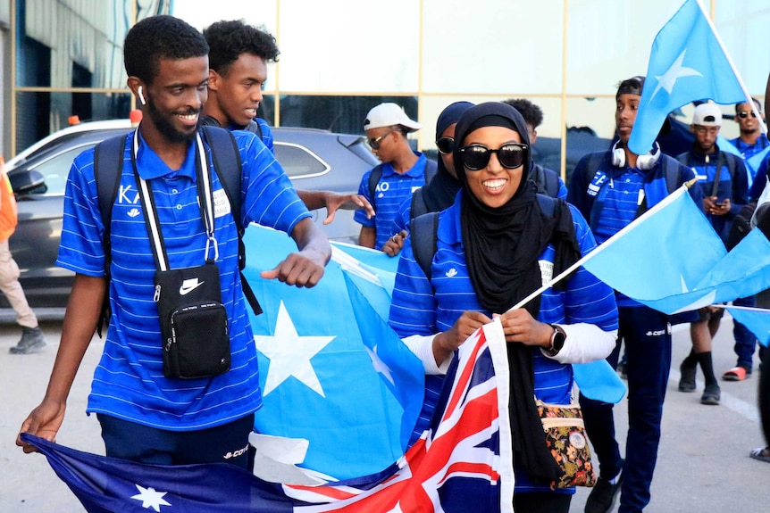 Amina Liban walking with other African-Australians holding an Australian flag.