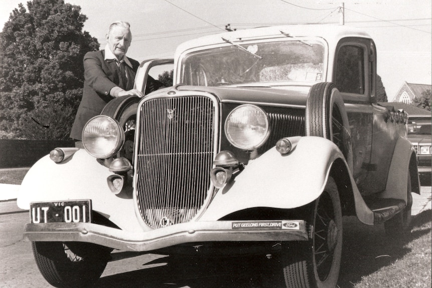 Photo black and white of a man with an older car.