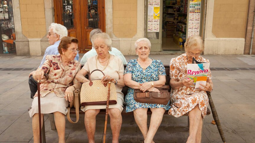 Four elderly female friends hang out in a small square
