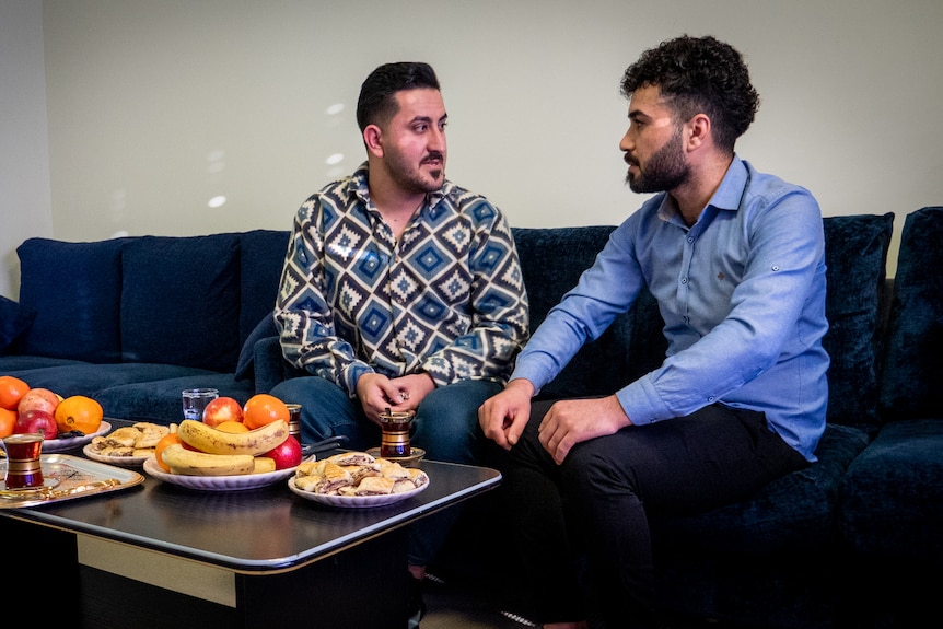 Support worker Nayif Rasho talking with Anas Khalaf on couch in house in Toowoomba, June 2023.
