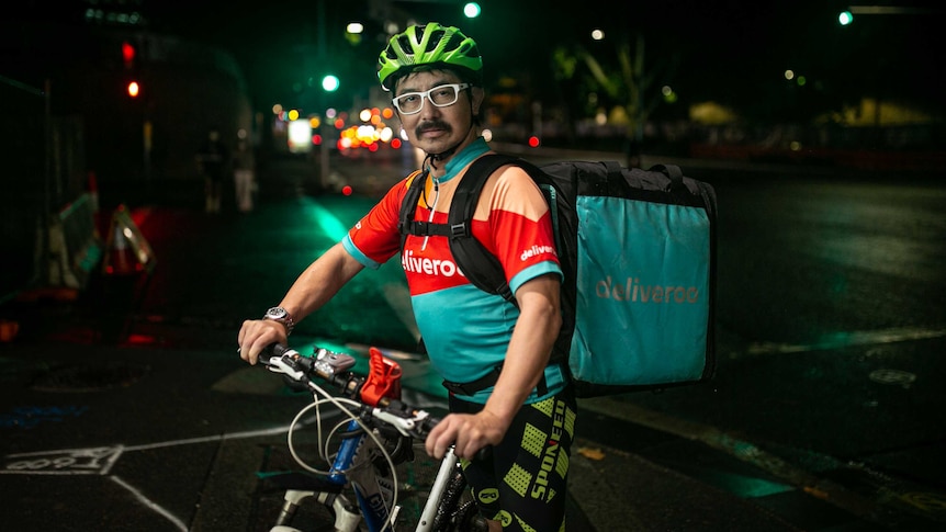 a man on a bike at the the traffic lights with deliveroo