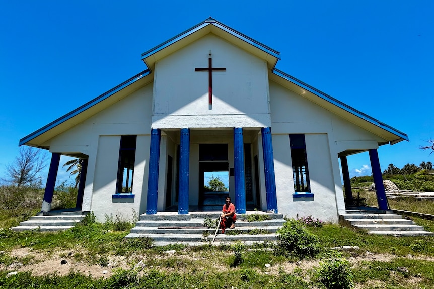 A woman sitting in front of an abandoned church