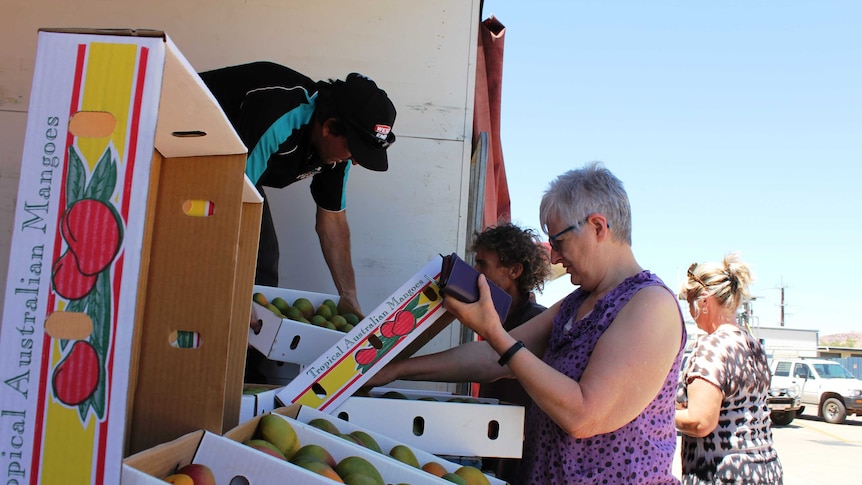 A close shot of people buying mangoes from a roadside shop in Alice Springs
