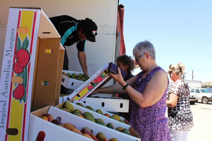 A close shot of people buying mangoes from a roadside shop in Alice Springs