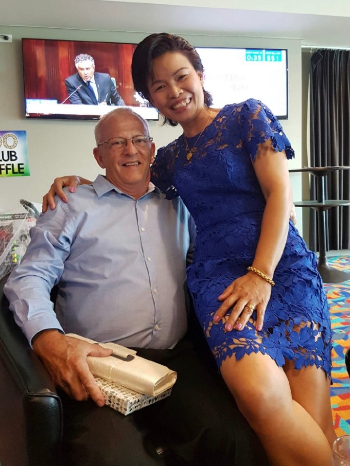 A woman sits on a man's arm chair.