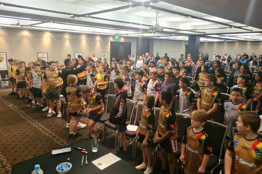 A number of kids sitting in rows of chairs