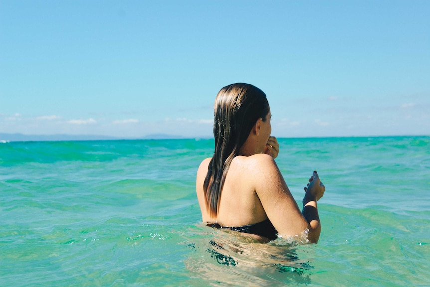 Woman stands in water at the beach