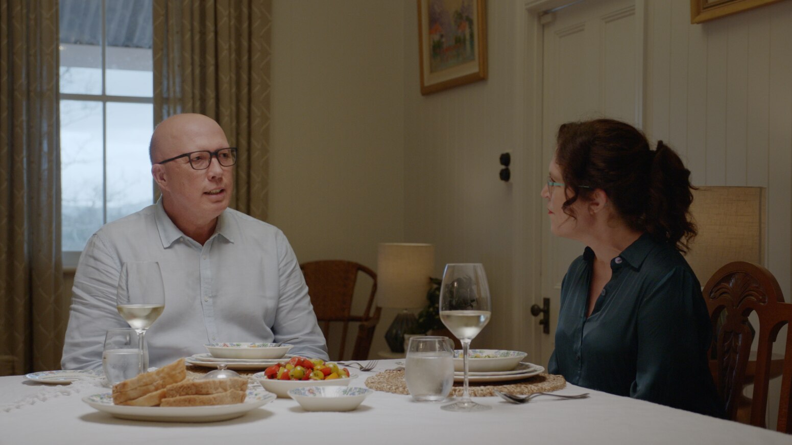 Peter Dutton and Annabel Crabb sitting at a dining table with two glasses of wine and dishes in front of them