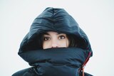 Face of woman in hoodie with a puffer jacket against a white background 