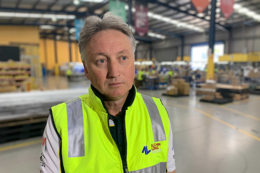 A man wearing a yellow high-vis vest standing on a factory floor
