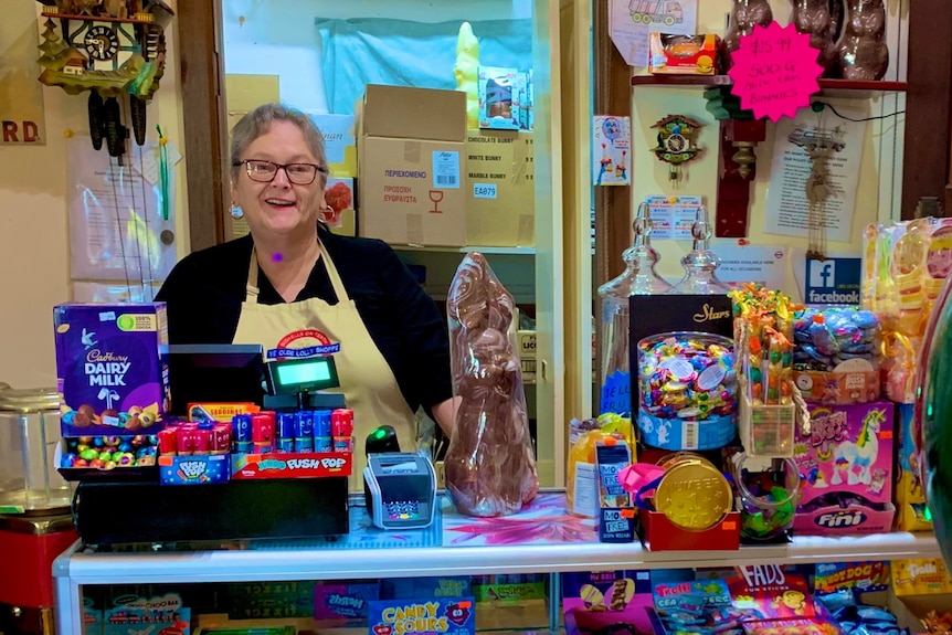 A woman behind the counter of a lolly shop.