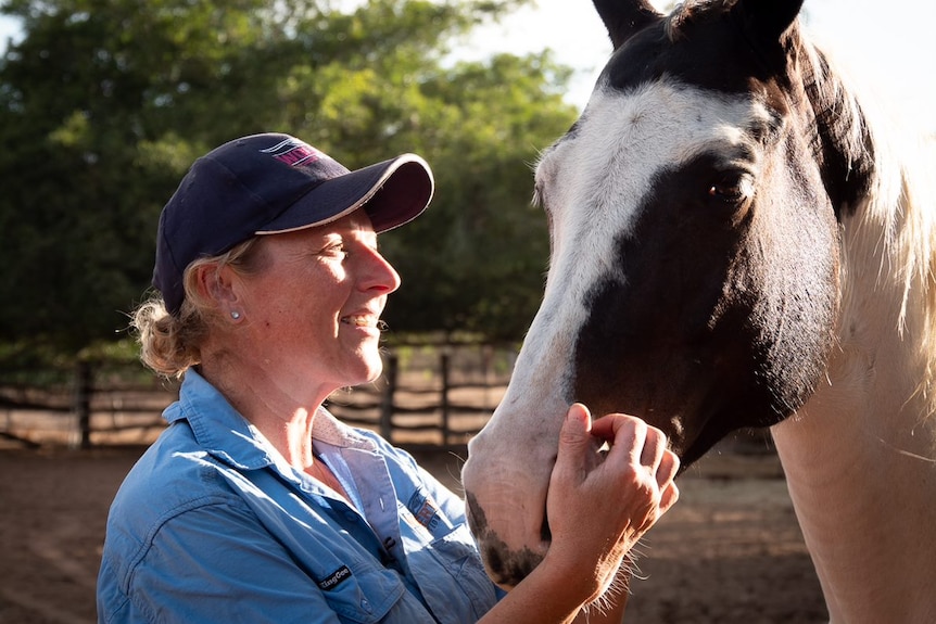 A woman patting a horse