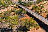 aerial view of a car crossing a bridge in an outback setting