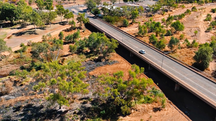 aerial view of a car crossing a bridge in an outback setting