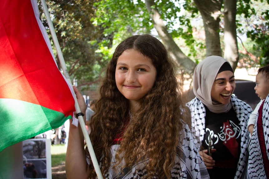 a young girl holds a palestinian flag at a rally in sydney on saturday october 21