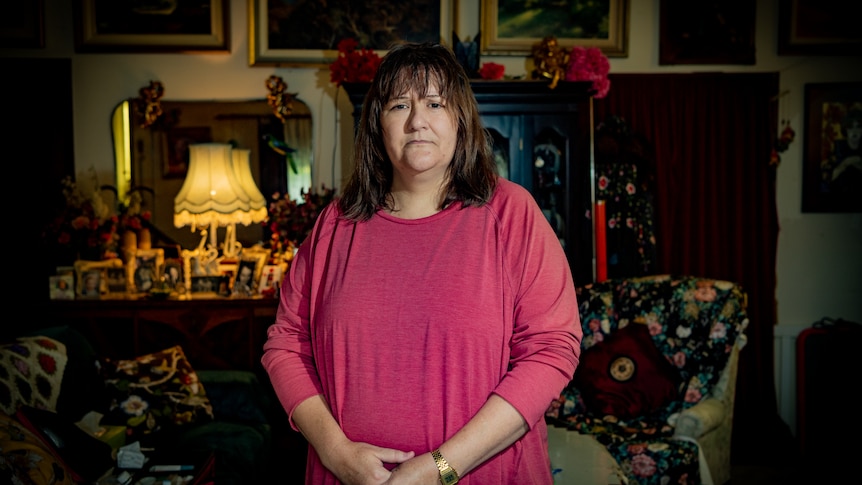 A woman in a pink blouse standing and looking at the camera