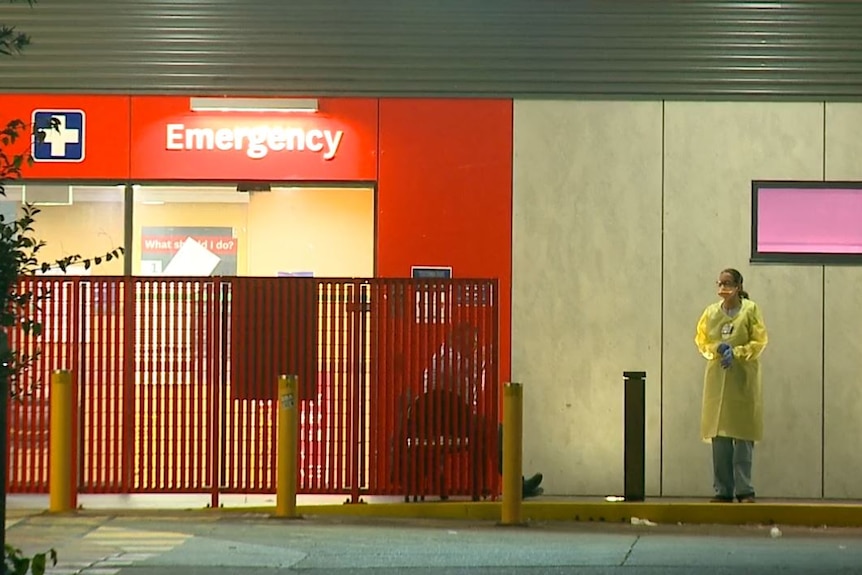 A woman in PPE stands outside the emergency department