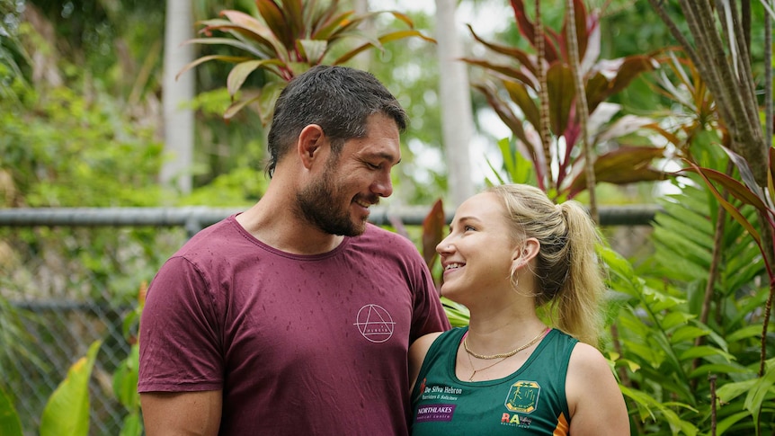 Lennair and Aidan Hill smile at each other. Behind them is their leafy green backyard.