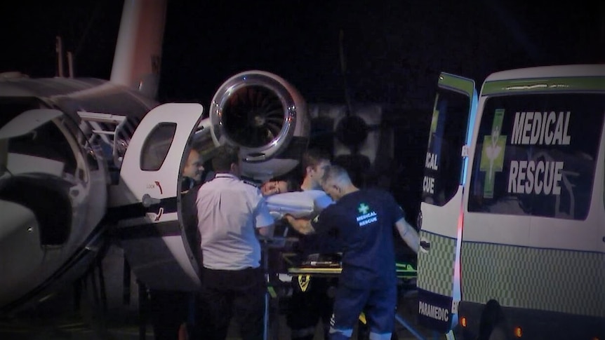 A man is wheeled off a plane and into an ambulance