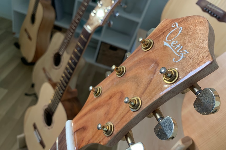 A close-up of the tuning pegs of a guitar, with others in the background.