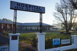 An entry sign reading 'hospital keith and district' with a building and trees in the background
