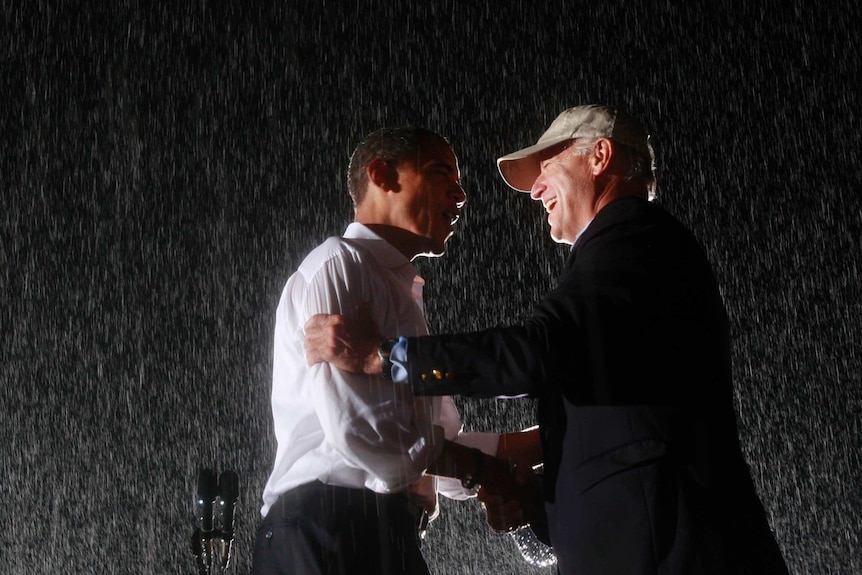 Barack Obama and Joe Biden embrace in the rain during a campaign rally