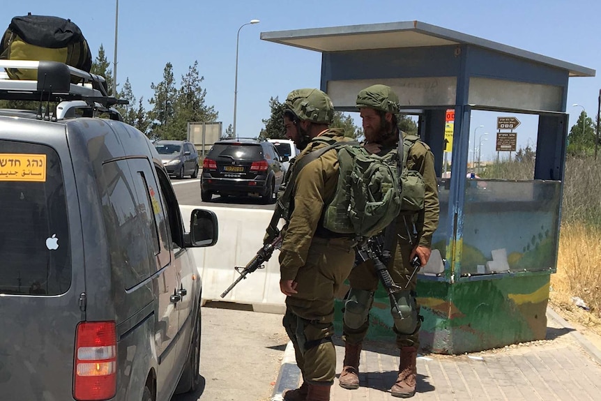 Two soldiers stop a Palestinian's car at a checkpoint near Gush Etzion.