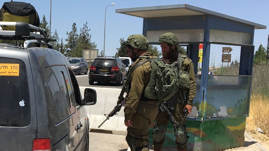 Two soldiers stop a Palestinian's car at a checkpoint near Gush Etzion.