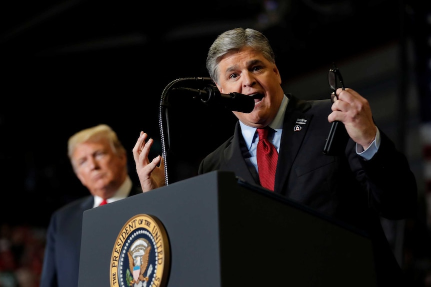 Sean Hannity speaking at a podium with Donald Trump in the background